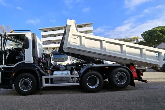 Porteur 6x4 avec bras de levage et benne levée, vu de côté